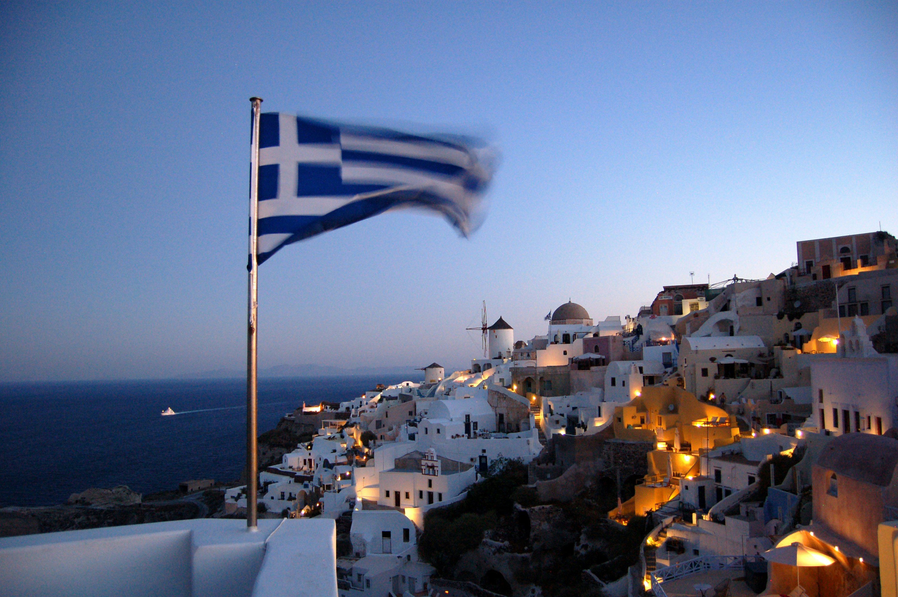 Greek flag waving in Oia Greece at night.